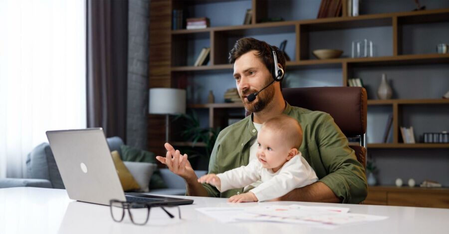 Homem trabalhando home office com seu filho no colo. Reprodução: Internet